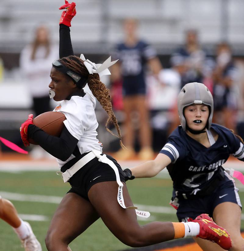 Harlem’s Hari Young runs past of Cary-Grove's Aria Stanton during an IHSA McHenry Sectional semifinal girls flag football game on Monday, Oct. 13, 2025, at McCracken Field in McHenry.