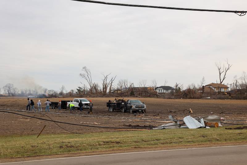 People work to clean up debris in a field along Waldron Road in Aroma Township on March 14, 2026, following the March 10 tornado in Kankakee County.