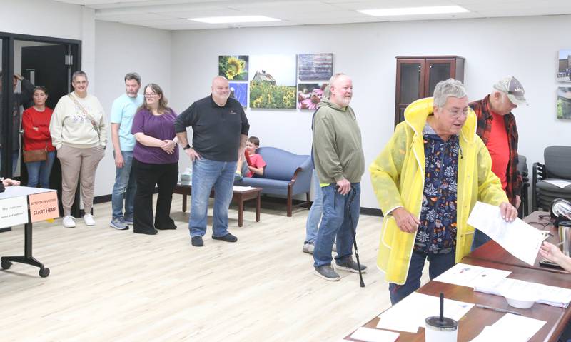 Judy Stout (right) receives her ballot from election judges as a long line of voters wait out the door during the election on Tuesday, Nov. 5, 2024 at the Village Hall in Utica.