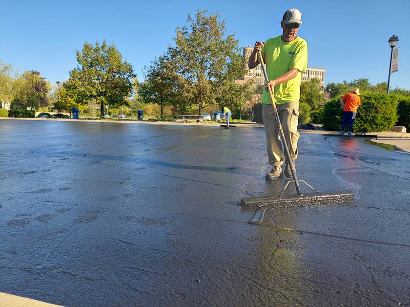Nicholas Stanmar, of Ski Seal Coating and Maintenance of La Salle, volunteers his time Tuesday, Oct. 3, 2023, resurfacing the parking lot at the Middle East Conflicts Wall in Marseilles.