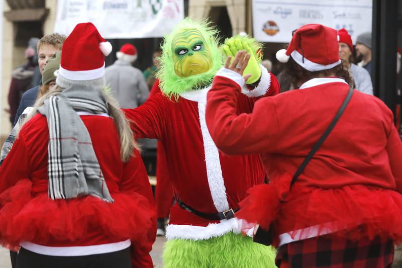 Russ Hyatt of Sundowner Entertainment, dressed as the Grinch “high fives finishers during the McHenry County Santa Run For Kids on Sunday morning, Dec. 3, 2023, in Downtown Crystal Lake. The annual event raises money for agencies in our county who work with children in need.