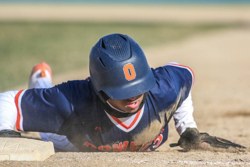 Oswego's Kam Jenkins (25) dives back into first during a pickoff attempt during baseball game between Plainfield South at Oswego on Monday, April 14, 2025 in Oswego.