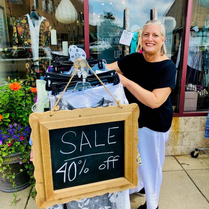 The staff at VENI VIDI VAL gets ready to display merchandise outside the store at the 2023 village-side sidewalk sale.