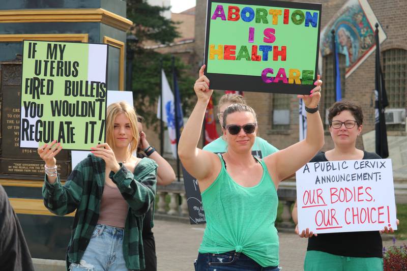 Hannah Walker, 14, of Kingston (left), stands in protest Monday, July 4, 2022, alongside Michelle Walker of Kingston  (middle) and Jen Barton of Genoa (right) during a reproductive rights demonstration staged in downtown DeKalb. The Independence Day gathering was organized to protest a recent ruling by the U.S. Supreme Court that struck down Roe v. Wade, which protected access to abortion under federal law.