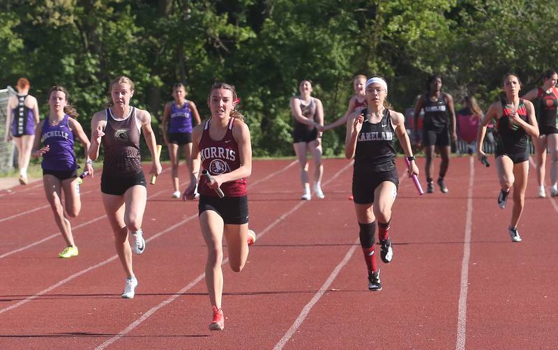 (From left) Rochelle's Alex Neece, Sycamore's Alyssa Stacy, Morris's Ava Conley, Kaneland's Ellie Olp and L-P's Ava Currie compete in the 4x100 relay during the Interstate 8 Conference girls track championship on Friday, May 9, 2025 at Morris High School.