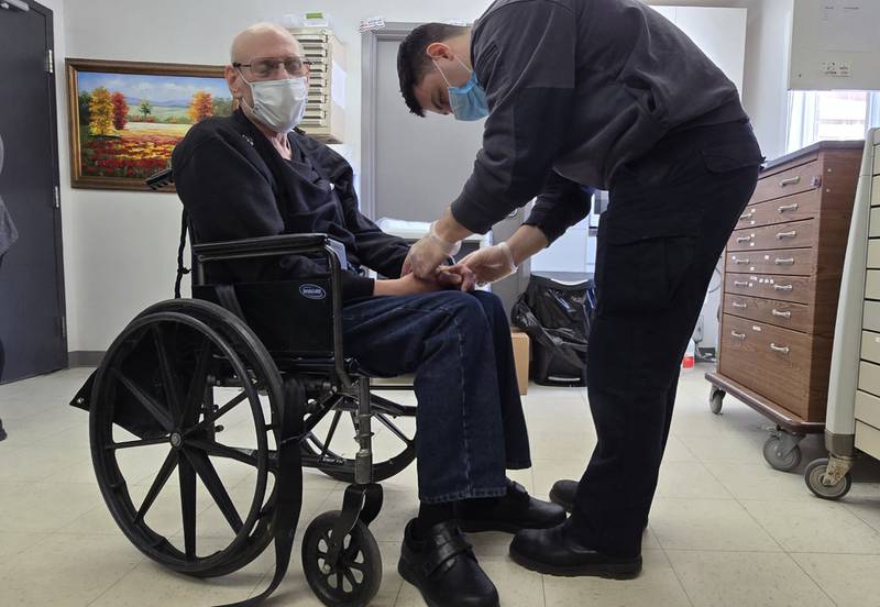 Kyle Albert, McHenry County College student in the paramedic certification program, assists a resident at Sheltered Village in Woodstock as part of his clinical rotation.