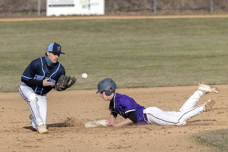 Dixon’s Bryce Feit slides in safely as second baseman Jacob Smith plays the ball on a steal Monday, March 20, 2023 against Rockford Guilford.