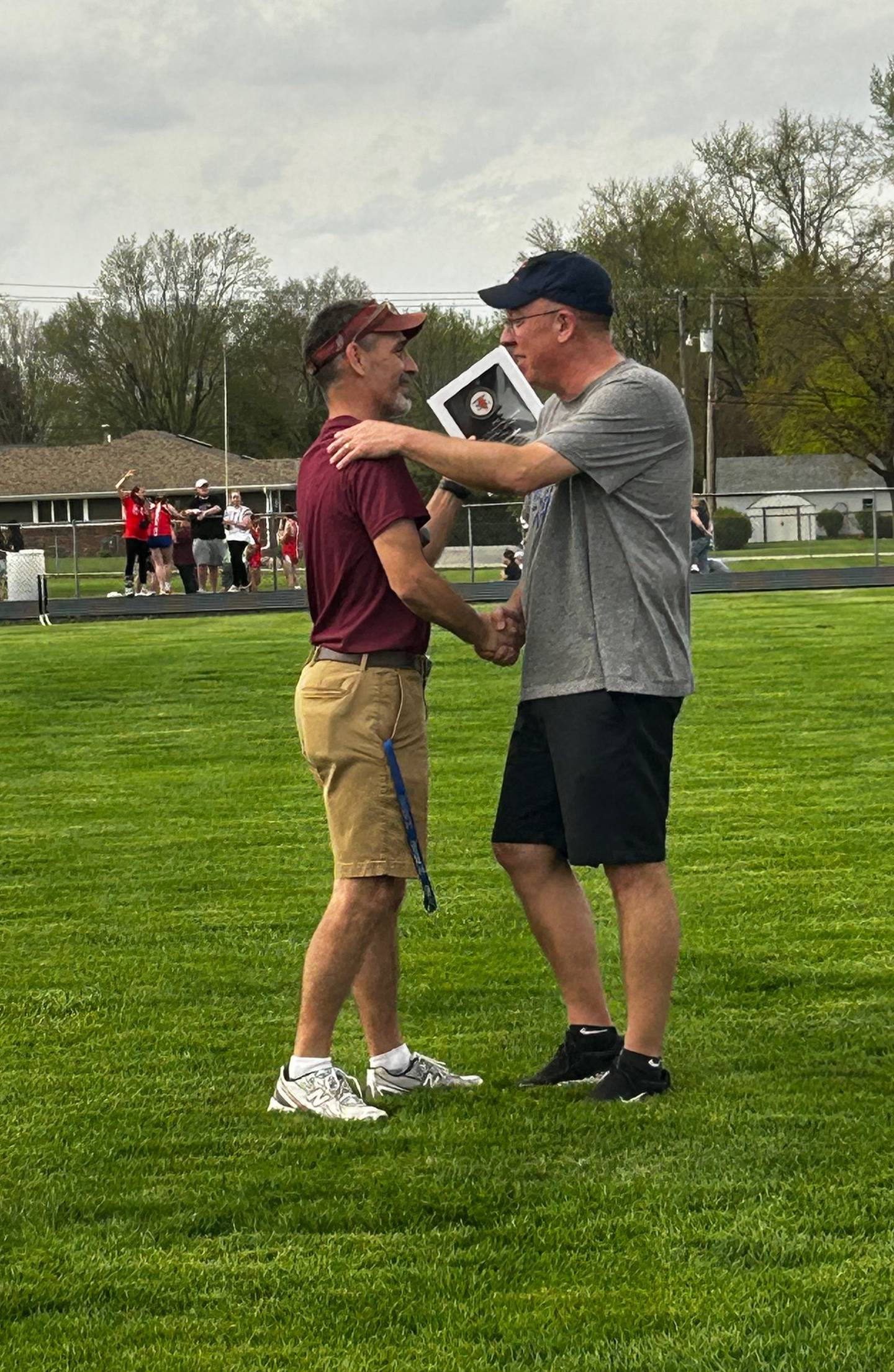 Watseka girls track and field coach Troy Mitchell (left) presents Tom Schroeder with a Distinguished Service Award from the Illinois Track and Cross Country Coaches Association before a meet on Monday, April 13, 2026.