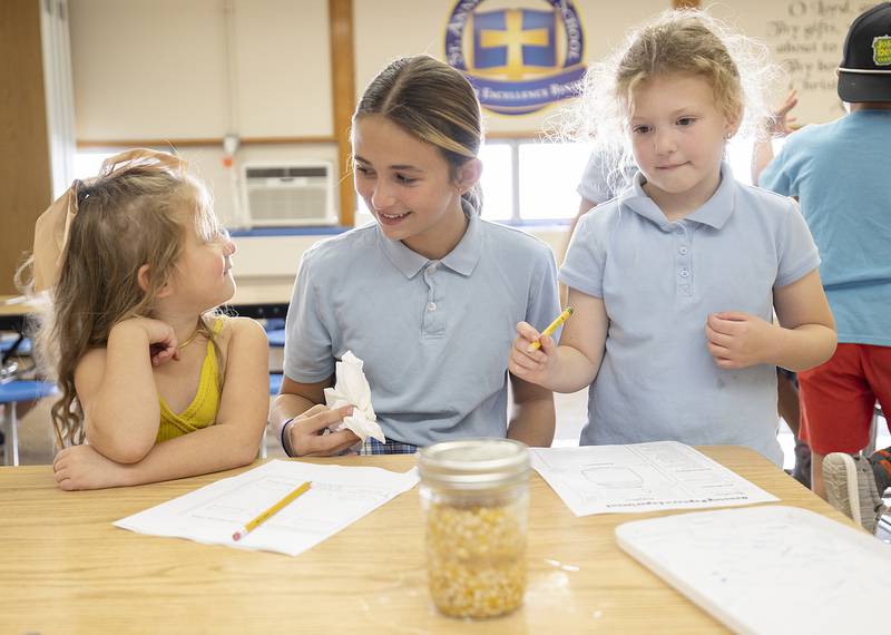St. Anne’s sixth grader Raelie Bilharz helps preschooler Rosalee Lawrenz (left) and kindergartener Lois Westphal with an experiment Thursday, October 10, 2024, at the school.