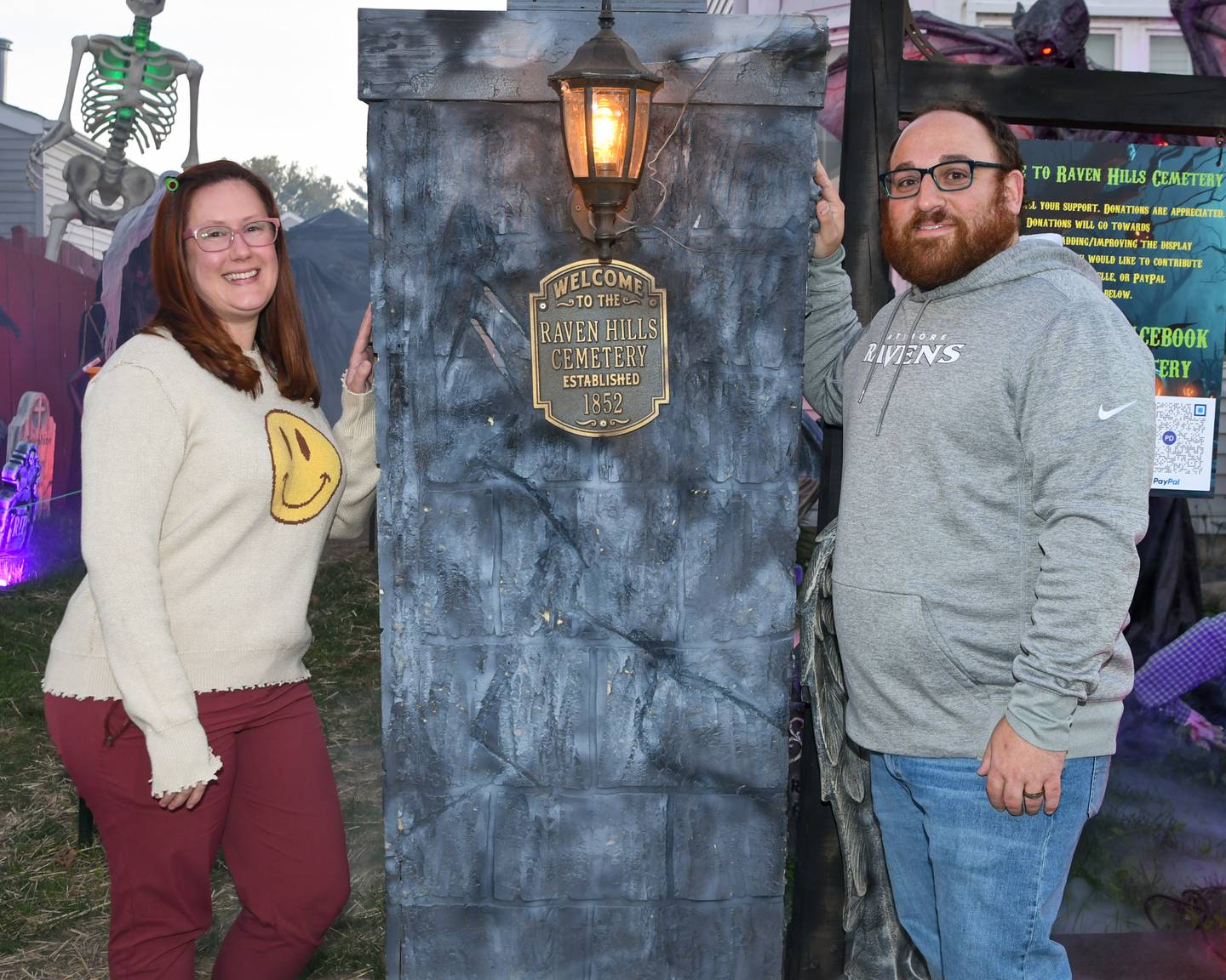 Phil, right, and his wife Dannielle Dienoff pose for a photo in front if a pillar that Phil made and are on display on Wednesday Oct. 16, 2024, that sits outside his home in Oswego that is part of his haunted yard trail.