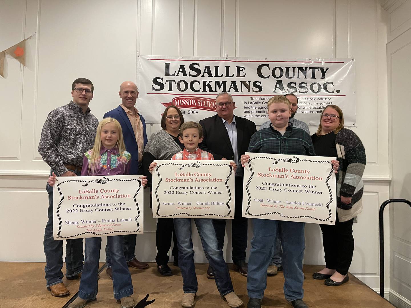 Winners of the essay contest Why I Want to Win-A-Show Animal are (front) Emma Lukach, sheep; Garrett Billups, swine; Landon Uzumecki, goat. They are joined by sponsors (back row) Nick Angus, Edgewood Farms, Riley Hintzsche, Streator High School FFA; Laura Patyk and Terry Patyk, Patyk Farms and Livestock; Matt and Kerri Swain.Absent from the photo is Tenley Pyszka, beef winner.