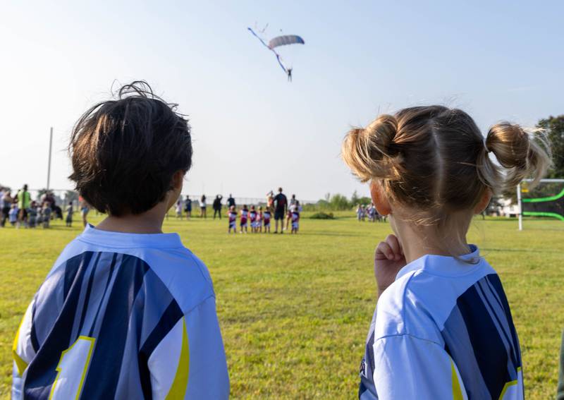 Ottawa Soccer Club players watch as skydivers from Skydive Chicago land at the East McKinley Fields in Ottawa Saturday, Aug. 19, 2023, morning during the opening day celebration.