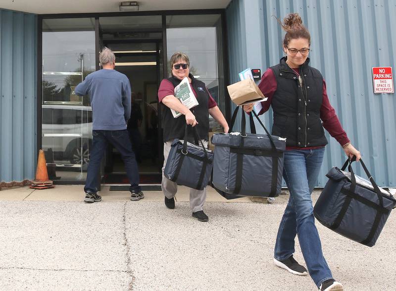 Volunteers Stephanie Barring (left) and Chris Sauter, both from DeKalb, pick up a Meals on Wheels delivery to distribute Tuesday, April 23, 2024, at the Voluntary Action Center in Sycamore. VAC is celebrating its 50th anniversary this year.