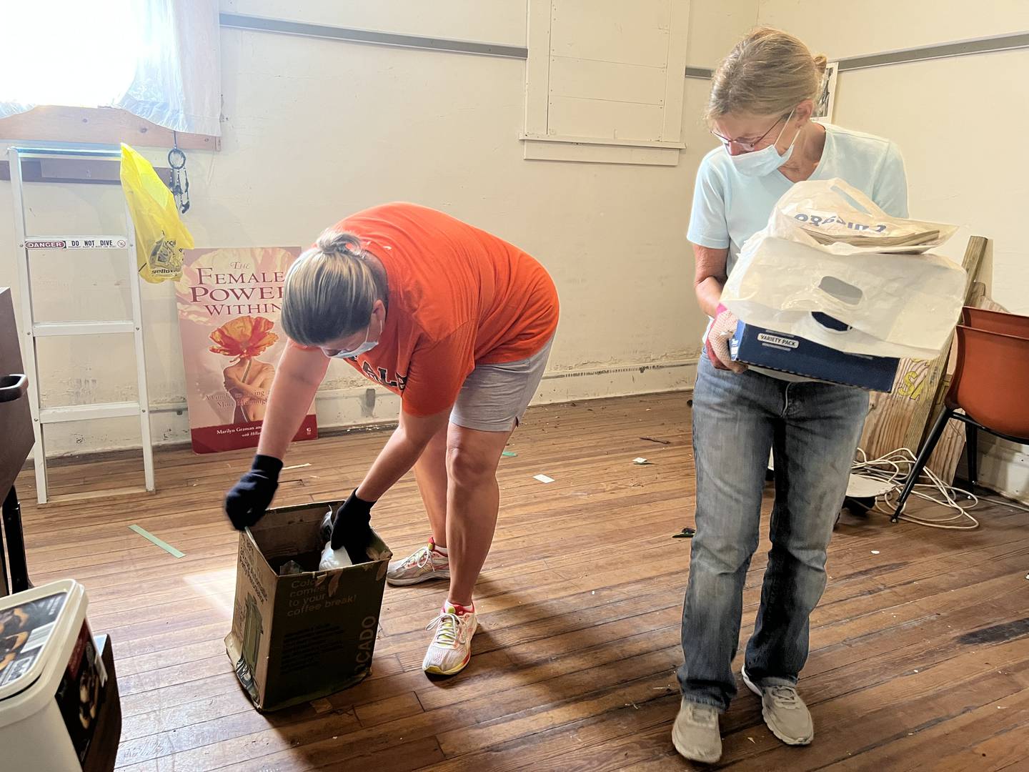 Ann Mueller watches Michelle Perkins sort through a waterlogged box in the basement of the DeKalb Area Women's Center on Aug. 24, 2022.