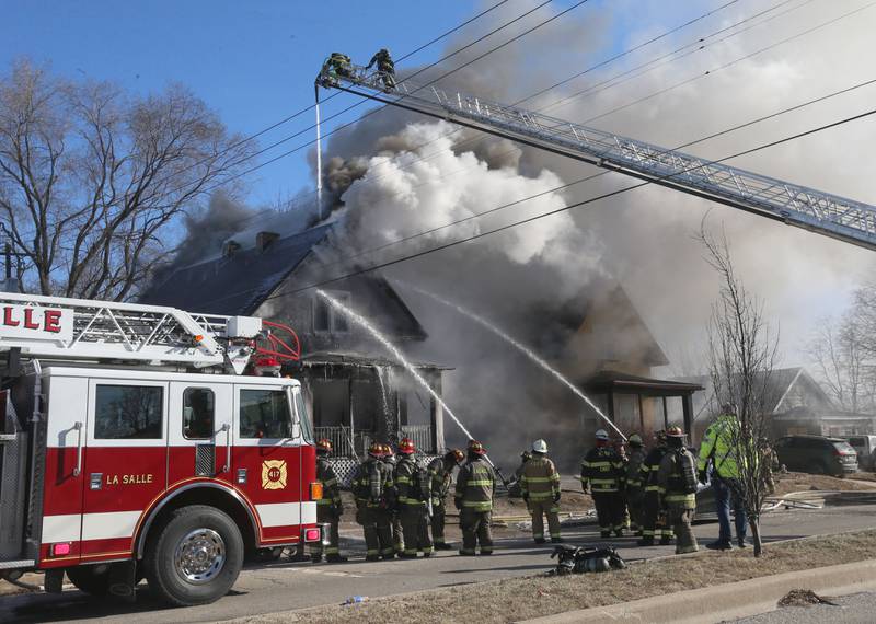 Heavy smoke billows from the roof  as firefighters dump water on a fully engulfed home in the 800 block of Bucklin Street on Friday, Jan. 23, 2026 in La Salle.