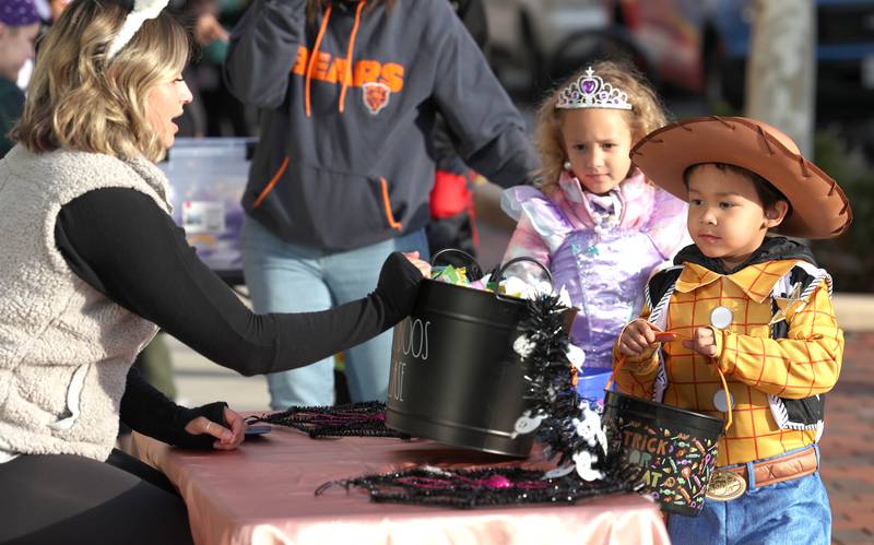 Gianna Burdick, manager of Canvas Hair Studio, lets Mia Shelton, 5, and Ezra Jones, 4, from DeKalb, pick out their candy in front of the salon  on Lincoln Highway in downtown DeKalb Thursday, Oct. 27, 2022, during the Spooktacular trick-or-treating event hosted by the DeKalb Chamber of Commerce.