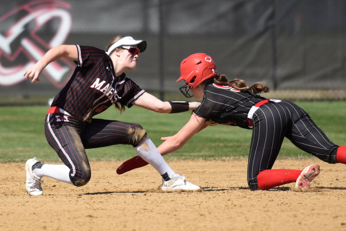 Marist's Mary Fortner, left, reaches to field a wide throw as Bradley-Bourbonnais' Shannon Lee dives in to steal second base during a game at Bradley-Bourbonnais Saturday, March 21, 2026.