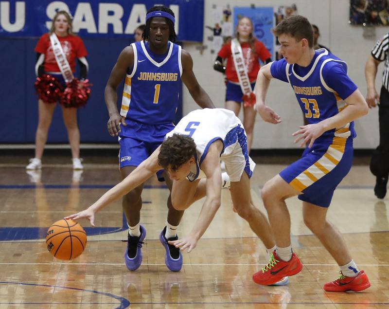 Woodstock's Maxwell Beard is tripped as he brings the ball up the court between Johnsburg's Jarrel Albea (left) and Johnsburg's JT Schmitt (right) during a Kishwaukee River Conference basketball game on Friday,  Feb. 14, 2025, at Woodstock High School.