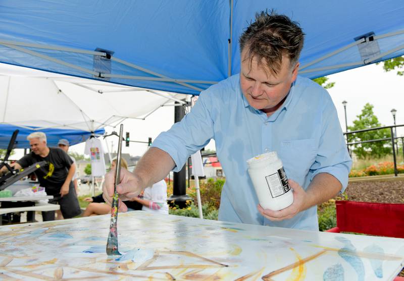 Lewis Achenbach creates an art piece during the Andy Warhol’s birthday celebration at the Wheaton French Market on Saturday, August 5, 2023.