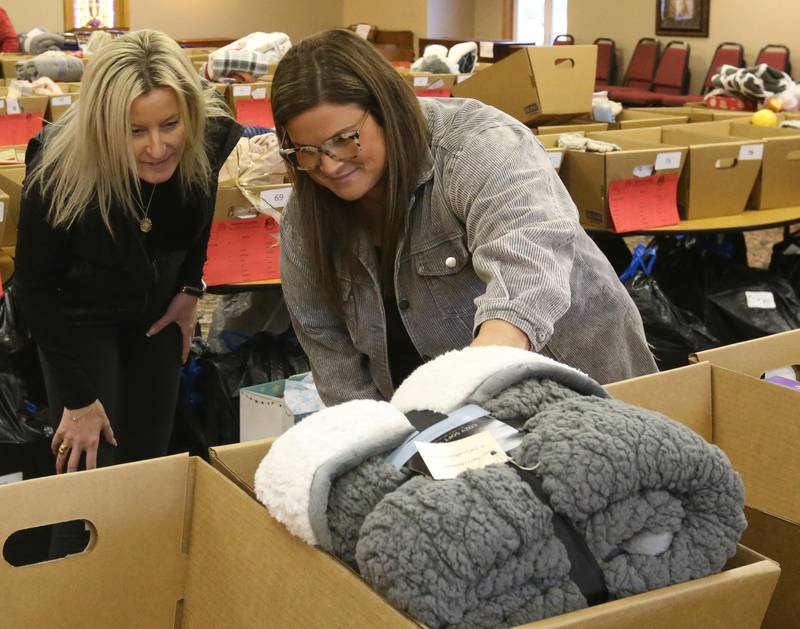 Amy Cimei and Karissa Hopkins check a tag on a basket on Thursday, Dec, 14, 2023 at the Putnam County Food Pantry in Granville. In collaboration with Toys in the Pantry, organizations, businesses, churches and schools from across the county the pantry is distributing Christmas baskets to local families in need. This is the 36th year the pantry has sponsored the basket project. The baskets contain food and gifts for children and senior citizens.