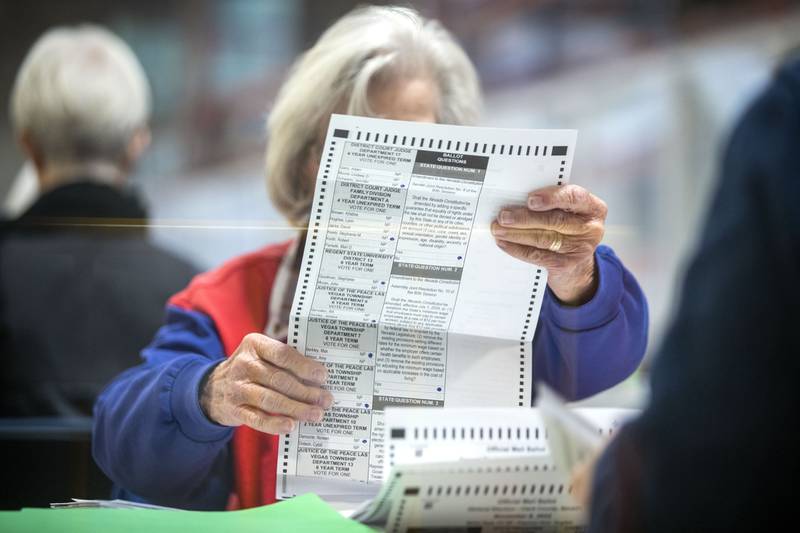 An election worker inspects a mail-in ballot in the count room at the Clark County Election Department in North Las Vegas, Saturday, Nov. 12, 2022.  Nevada's ballot count is entering its final act and may determine which party controls the U.S. Senate. (Steve Marcus/Las Vegas Sun via AP)