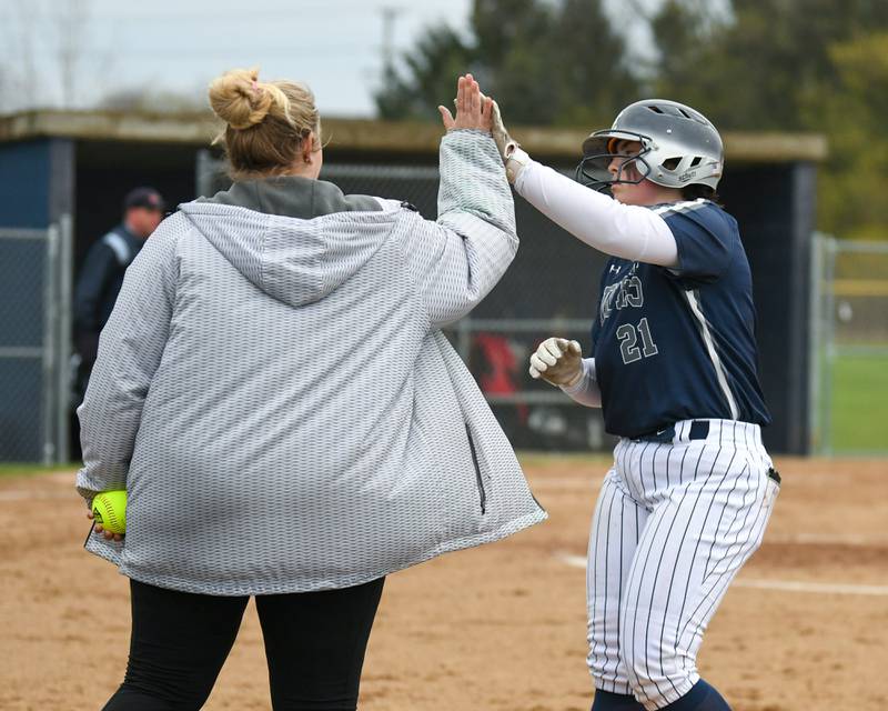 Oswego East’s Ryenne Sinta, (21) gets a high five from her coach after getting a base hit on Thursday April 17, 2025, while taking on Plainfield North held at Oswego East High School.