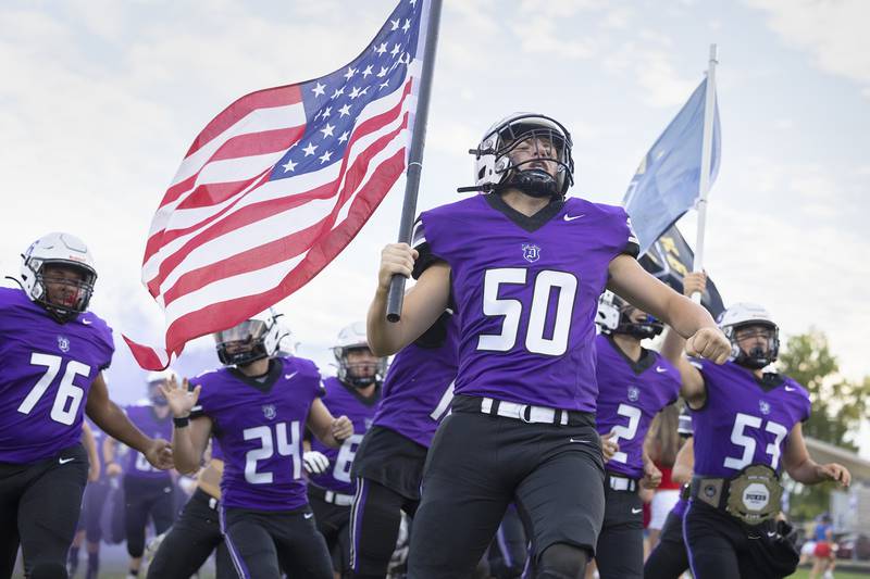 Dixon’s Aidan Hogard carries the American flag Friday, Aug. 30, 2024, as the Dukes take the field against Stillman Valley to start the 2024 football season.