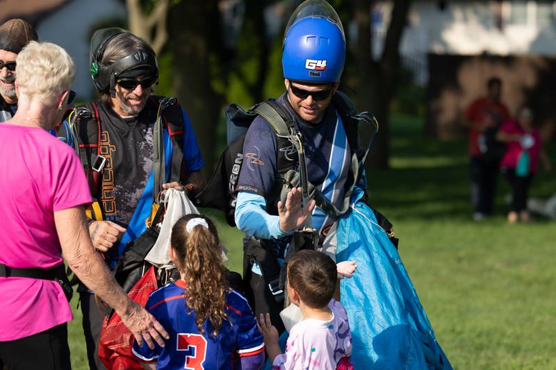 Skydivers Chad Starkel and Anthony Ebel of Skydive Chicago high-five kids at the opening day of youth soccer on Saturday, Aug 16, 2025, at Peck Park in Ottawa.