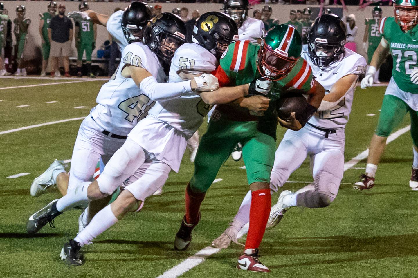 Marion Perich of L-P gets tackled by Caden Wicks and Christopher Larson of Sycamore on Friday, October 11, 2024 at Howard Fellows Stadium in LaSalle.