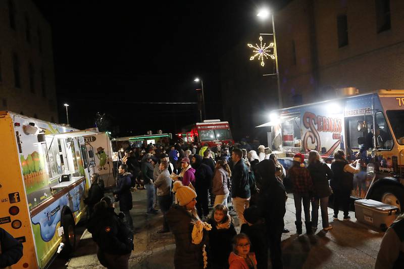 People line up to eat at some of the food trucks during the Lighting of the Square Friday, Nov. 25, 2022, in Woodstock. The annual event featured brass music, caroling, free doughnuts and cider, food trucks, festive selfie stations and shopping.