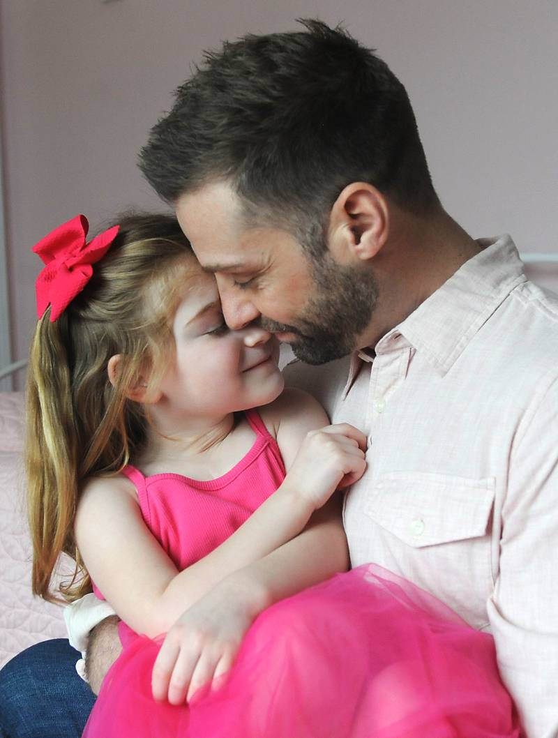 Everly Backe, 4, who has had multiple open heart surgeries to correct congenital heart defects, snuggles Friday, Feb. 11, 2022, with her dad, Matt, in their Crystal Lake home. As Everly has became more aware of her chest scar, which they call her "zipper," her father recently decided to get a tattoo that matches his daughter’s scar from her surgeries so she does not feel alone in having the scar.