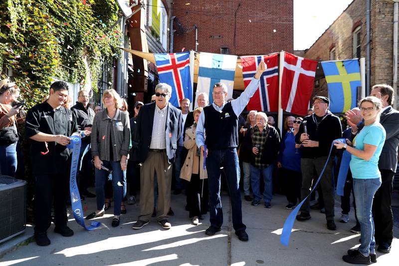 Mike Oleson (center), owner of Stockholm’s Restaurant and Brewery, cuts the ribbon to officially reopen the Geneva establishment after they were closed following a July fire.