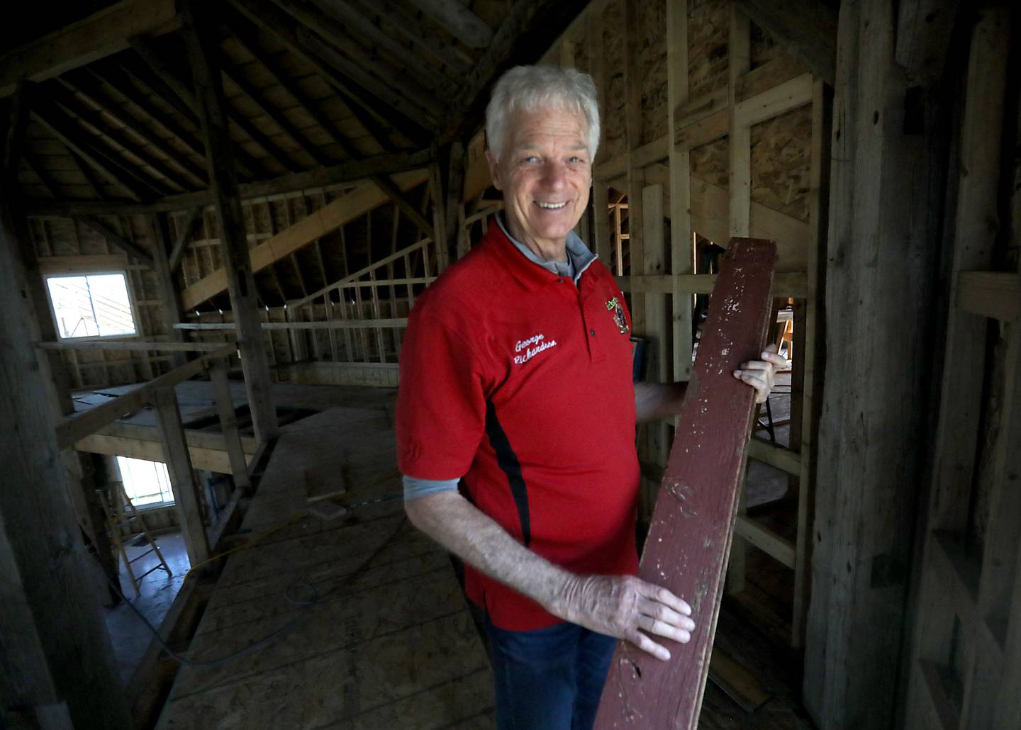 George Richardson, of Richardson Adventure Farm, holds an old piece of the original siding that is bringing  used for paneling inside the rare eight-sided barn is rebuilt at Richardson Adventure Farm Wednesday, April 22, 2026, in Spring Grove.