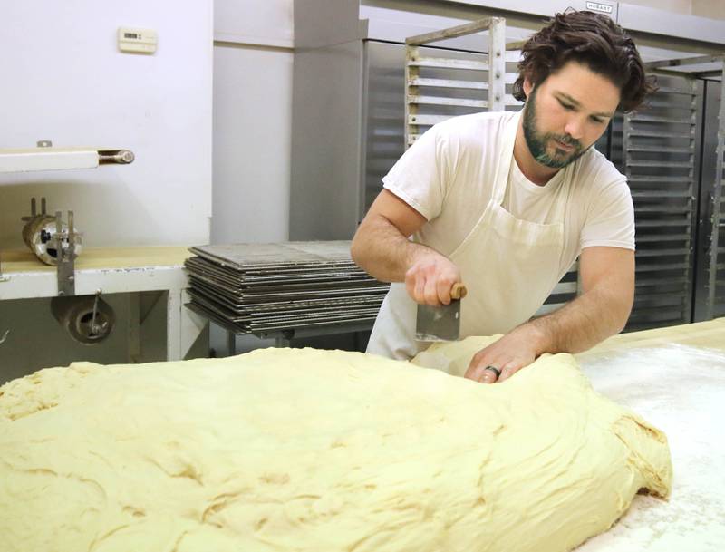 Eric Elleson, son of Ken Elleson, owner of Elleson's Bakery, cuts the dough into strips before it is sliced up for paczkis Monday, Feb. 28, 2022, in the kitchen of the bakery in Sycamore. Eric Elleson came in from Michigan especially for this day to help out his dad and members of his family who will be working all night making the paczkis from scratch to be ready at 5 a.m. tomorrow for Fat Tuesday.