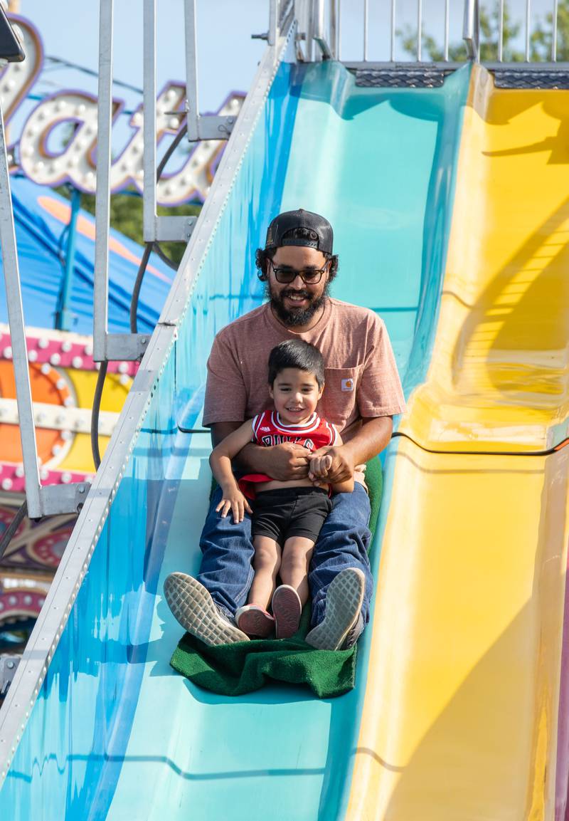 Arturo Recendez (back) and Arturo Recendez III, 2, (front) ride the Fun Slide at the DuPage Event Center & Fairgrounds on Saturday, July 30, 2022.