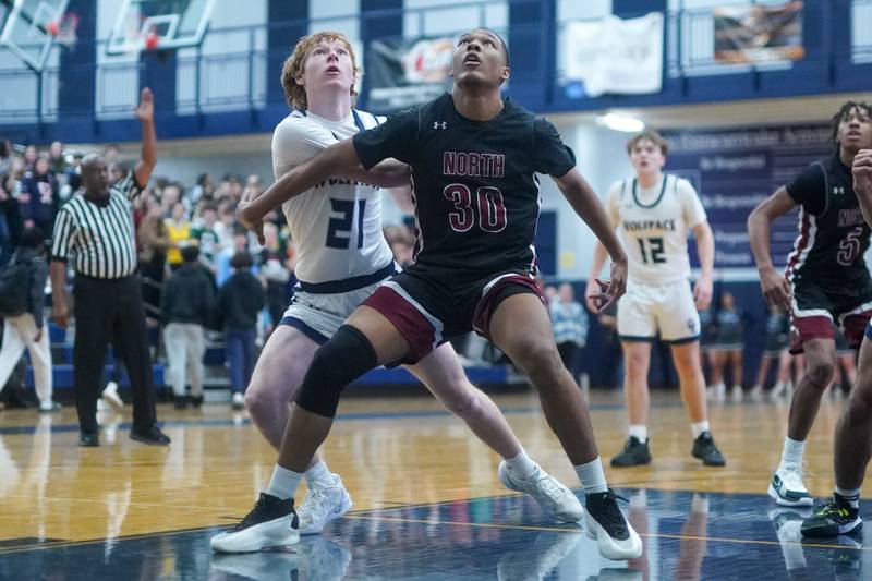 Plainfield North's Pierre Pointer (30) and Oswego East's Andrew Pohlman (21) fight for position under the basket during a basketball game at Oswego East High School on Friday, Dec. 6, 2024.