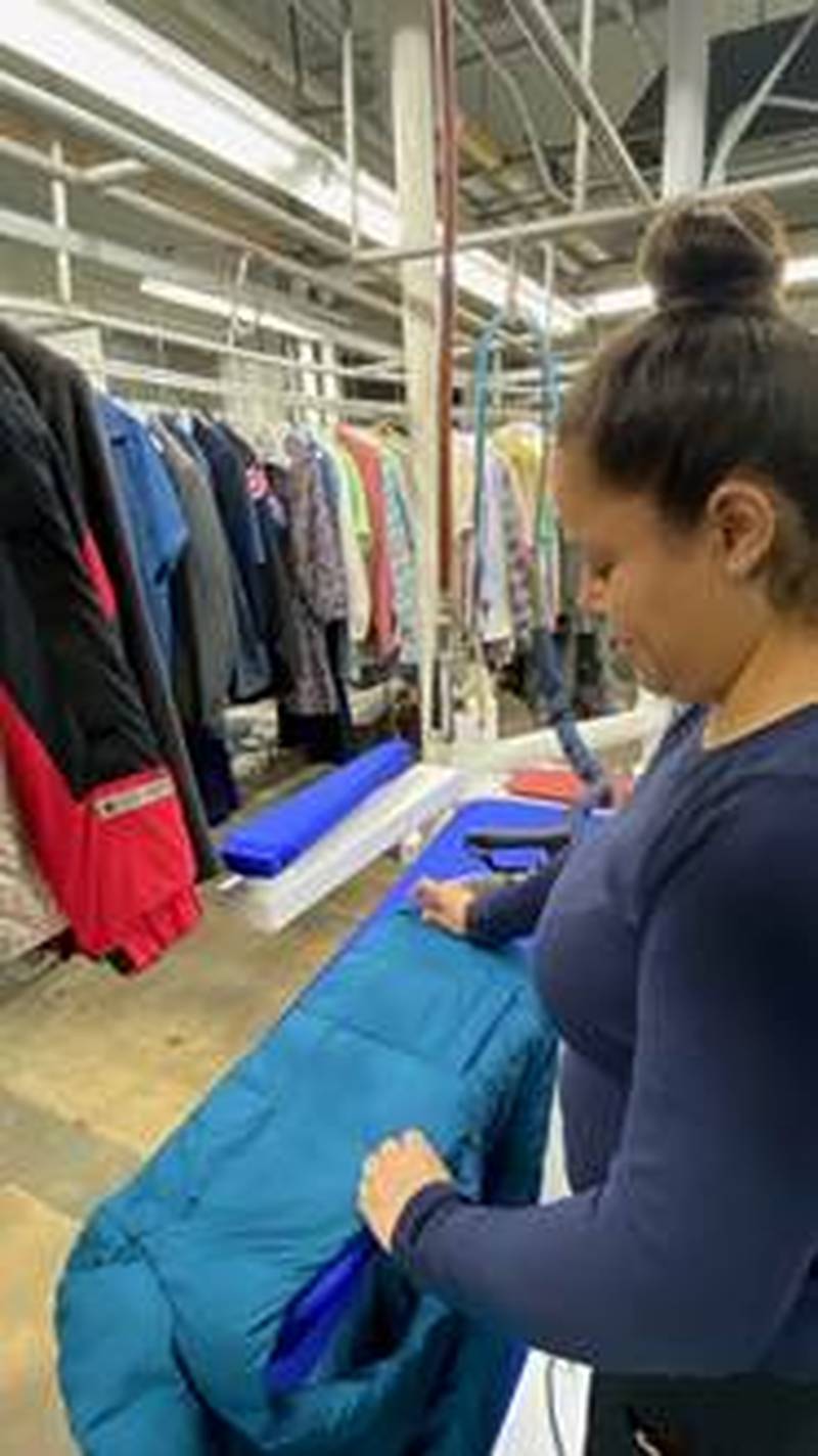 Itzel Castro of Zengeler Cleaners inspects one of the coats donated during the coat drive.