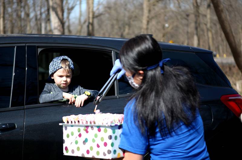 Pong Sayasane, director of the Bethlehem Preschool Center in St. Charles, safely hands out a lollipop to 5-year-old Deacon Jones on April 8. The school has been closed due to COVID 19 since March 17 and the teachers wanted to create a way that they could see the kids’ faces, say hi and give them something special for Easter.