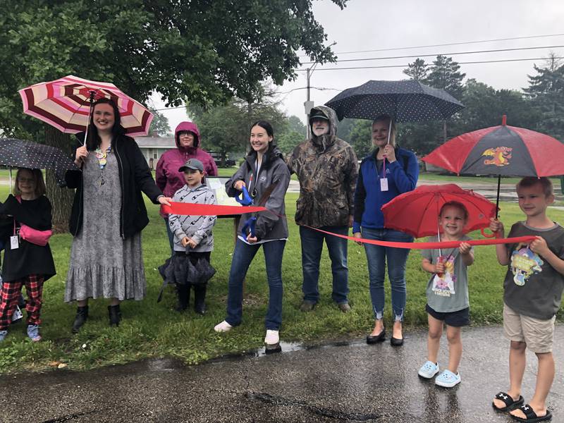 Hannah Bovino of the Cary Area Public Library cuts the ribbon on the StoryWalk June 1, 2024.