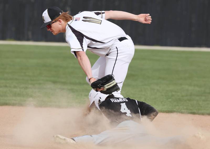 Kaneland's Zach Ramos slides in safely with a stolen base after the throw gets away from Sycamore's Teague Hallahan during their game Monday, April 22, 2024, at the Sycamore Community Sports Complex.