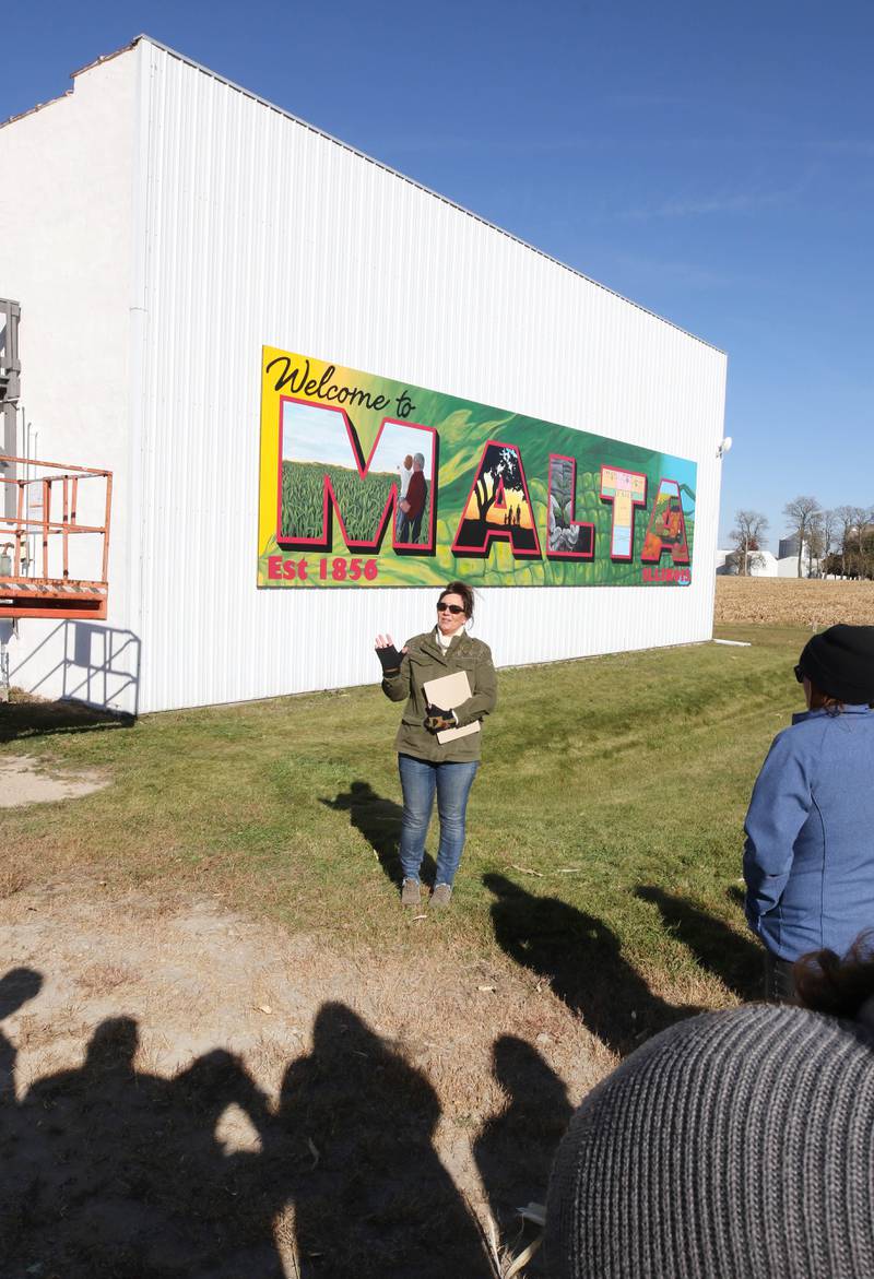 Jacque Fucilla, a member of the Malta Seedling Committee, talks about the new mural by Dixon artist Nora Balayti before the official ribbon cutting Wednesday, Oct. 19, 2022, on the north side of Route 38 in Malta. The mural, which spells out Malta in large capital letters, depicts the values of the town with themes of agriculture, family, community and growth.