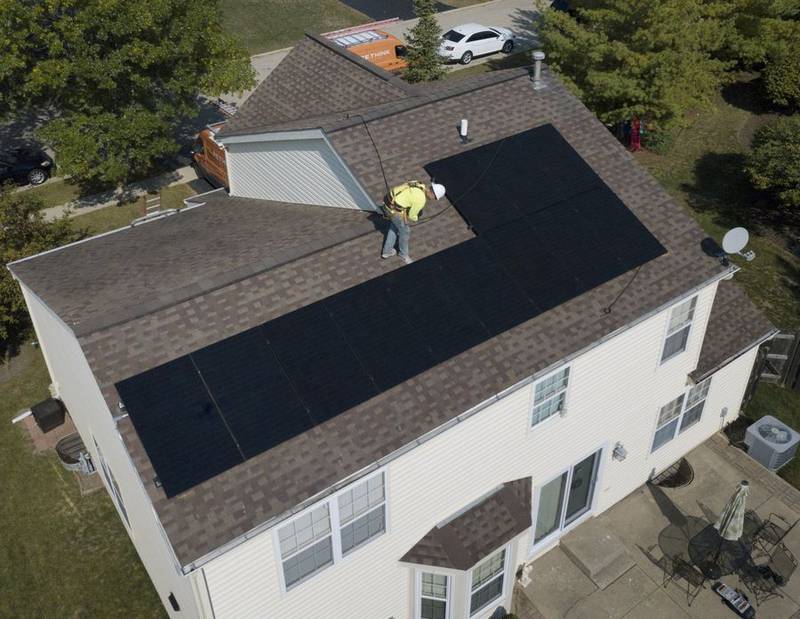 John Stewart, of Rethink Electric in Wood Dale, checks over the 12 solar panels that his company installed on the roof of a Grayslake home.