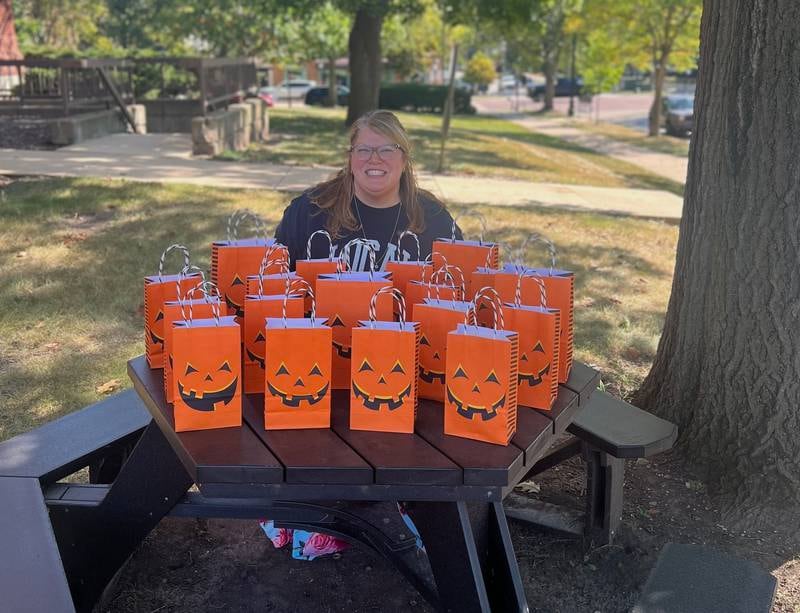 Autumn Fest Geneva organizer Kristen Cornelio with 70 gift bags containing local gift cards which will be given to various participating merchants for the seventh annual Autumn Fest Oct. 3 in downtown Geneva. The bags are to honor the recent passing of her father, who died two days before he would have turned 70.