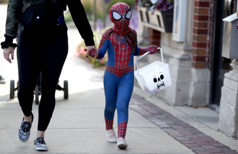 Spider Girl Violet Saracco, 5, collects candy while trick-or-treating throughout the Geneva business district on Thursday, Oct. 27, 2022.
