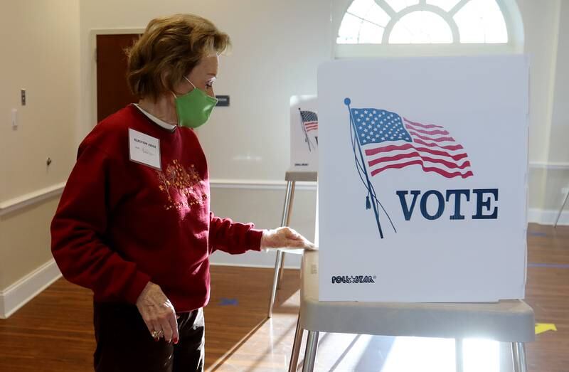 Election judge Vicki Ridges wipes down a recently-used voting station with a sanitizing wipe on Tuesday, Nov. 3, 2020 at Main Beach in Crystal Lake.