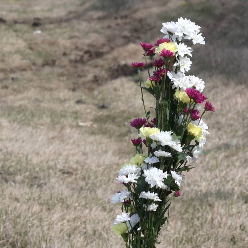 A memorial stands near visible ruts in the grass and skid marks Friday, March 29, 2024, at the site on Route 23 three-quarters of a mile south Perry Road, near DeKalb where a DeKalb County Sheriff’s deputy was killed in a crash early Friday morning.