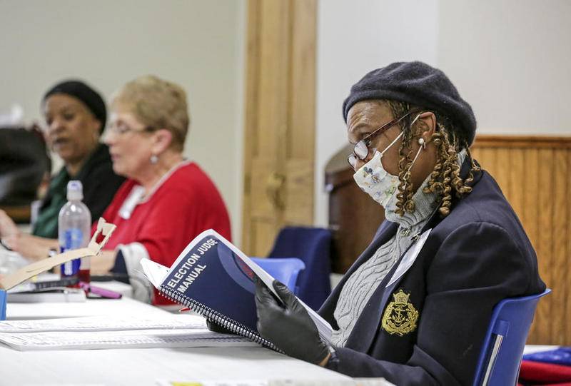 LeShawn Jordan reads through an Election Judge Manual on Tuesday, March 17, 2020, during Illinois' Primary Election at St. Mary Nativity Catholic Church in Joliet, Ill.