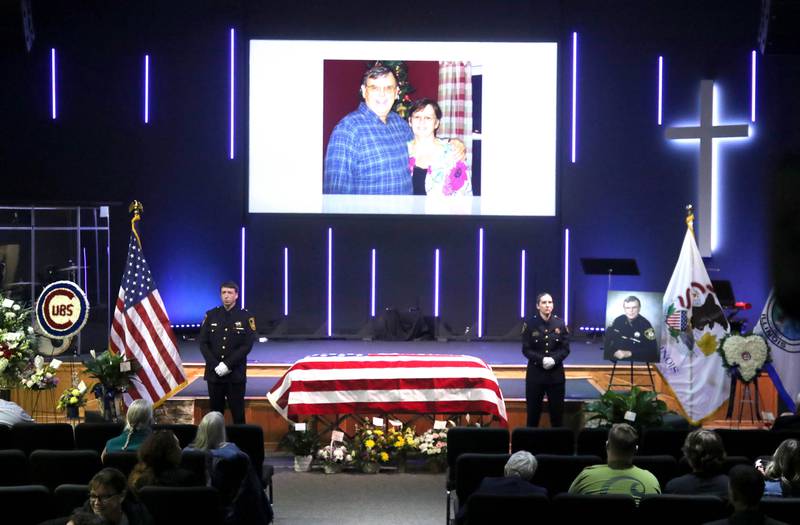 DeKalb County sheriff's deputies stand on either side of the casket of former DeKalb County Sheriff Roger Scott as a photo of him and his wife Marcia appear on the screen above during his visitation Thursday, March 6, 2025, at Bethany Road Bible Church in DeKalb. Scott, who was the county sheriff for more than 30 years, died on February 23 at the age of 78.
