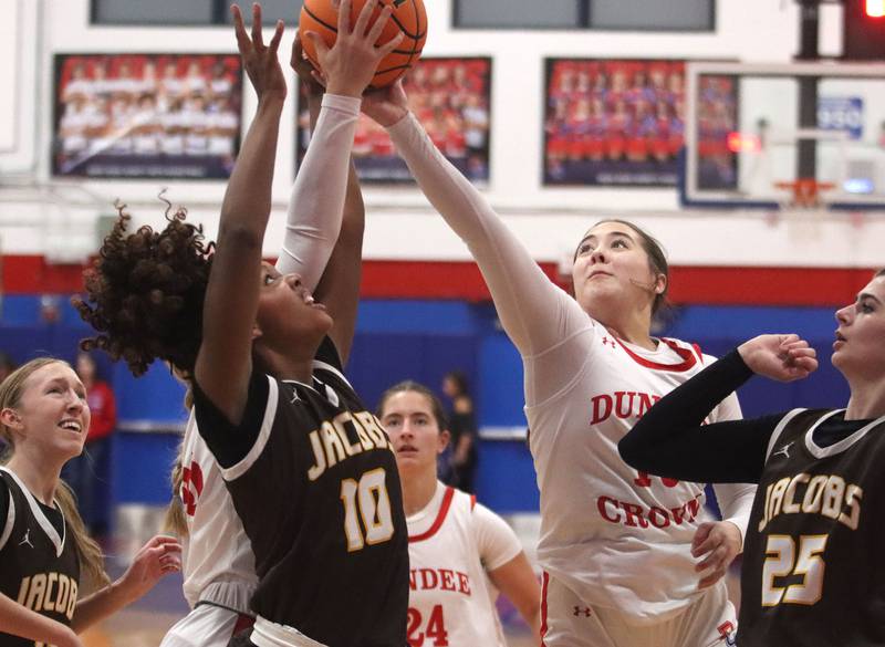Jacobs’  Zara Lewis, center left, battles Dundee-Crown’s Kate Graham, center right,  in varsity girls basketball on Friday, Dec. 12, 2025, at Dundee-Crown High School in Carpentersville.