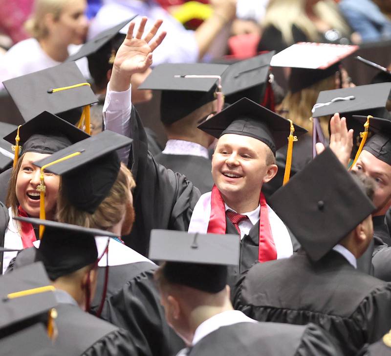 A soon-to-be-graduate waves to his family after finding his seat for the start of the ceremony Saturday, May 14, 2022, during the first of two undergraduate commencement ceremonies in the Convocation Center at Northern Illinois University in DeKalb.